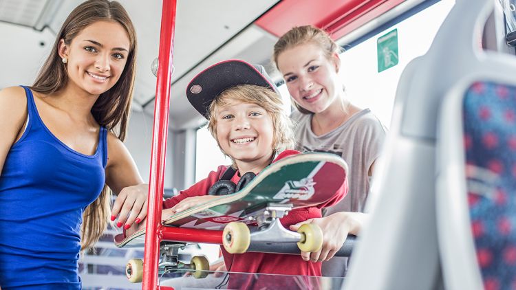 Junge mit Skateboard und zwei Mädchen im Bus